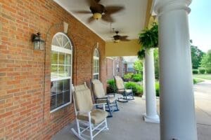 Porch with large white pillars, rocking chairs, ceiling fans, and hanging plants