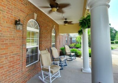 Porch with large white pillars, rocking chairs, ceiling fans, and hanging plants