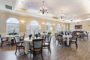 Large dining space with table and chair sets, centerpieces, windows, chandeliers, and hardwood floors