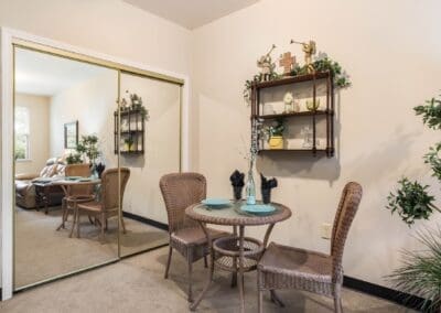 Dining area with table, two chairs, closet with sliding mirror doors, and several plants decorating the space